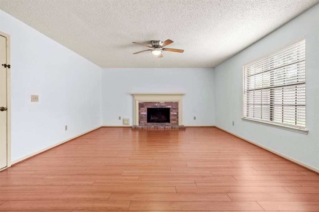 The spacious family room features a central fireplace and a large window with relaxing views of the private backyard.