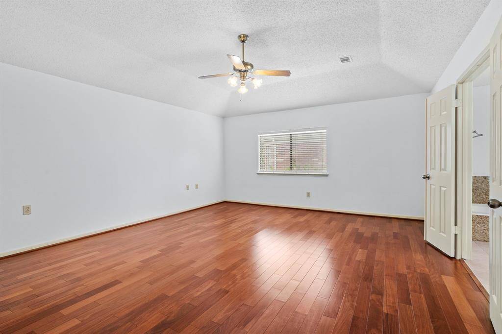 The expansive primary suite features vaulted ceilings, updated flooring, a lighted ceiling fan, and en suite bathroom.