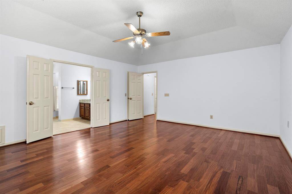Another view of the spacious primary suite which includes a large walk-in closet. Double doors lead to the en suite bathroom.