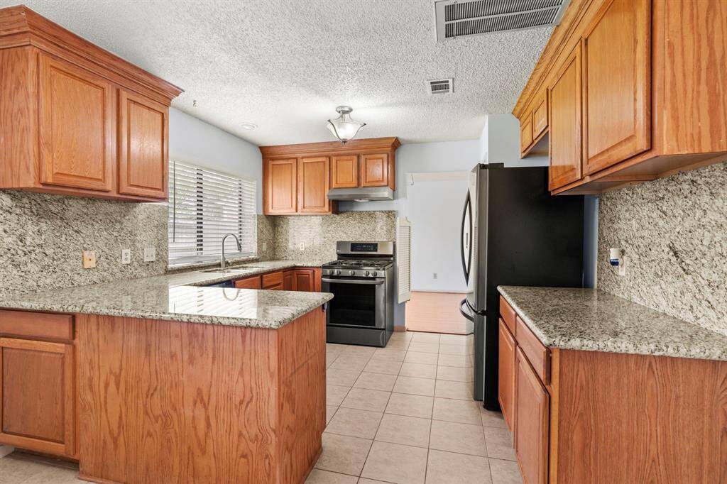 The kitchen includes recently installed stainless steel appliances including an LG Gas Range , Bosch dishwater, side by side refrigerator with dispenser, and NEW (April 2025) vent hood and pull-down sink faucet.