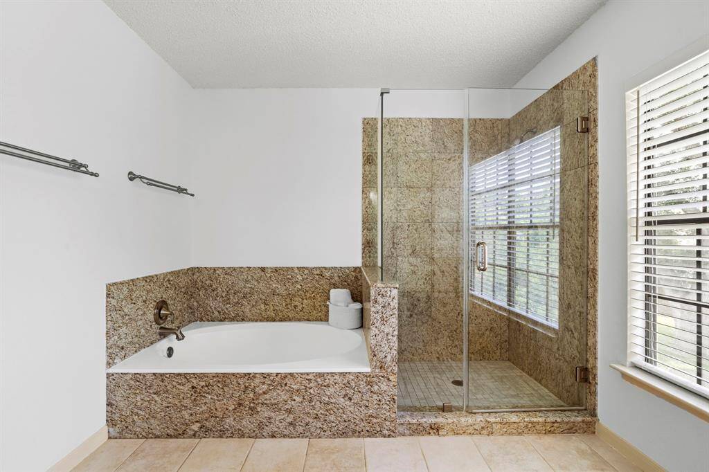 The updated en suite bathroom showcases a seamless glass walk-in shower and a soaking tub.
