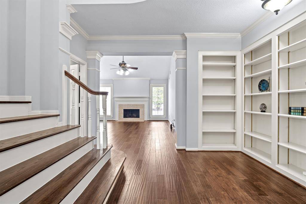 At the base of the staircase, a spacious landing doubles as a charming mini library, complete with built-in bookshelves that offer both function and character.