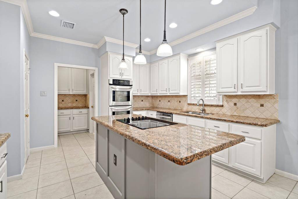 The kitchen is a chef’s dream with island cooktop, double convection ovens, mini breakfast bar, under-cabinet lighting, a large walk-in pantry, and a butler's pantry.