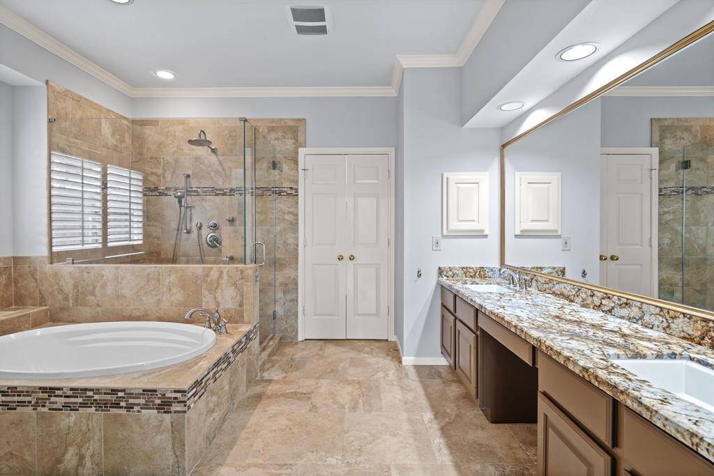 The spa-like primary bathroom offers a luxurious retreat, featuring a deep soaking tub, a sleek glass walk-in shower, an expansive dual vanity with a dedicated makeup area, a linen closet, a private water closet, and a generously sized walk-in closet.