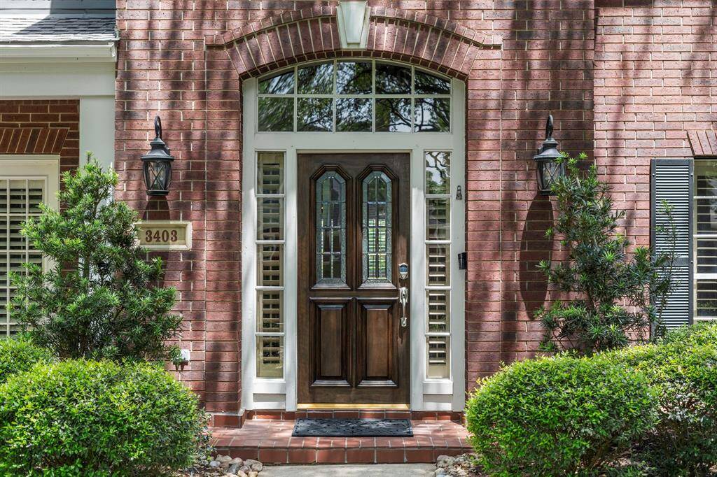 This elegant entry showcases a stately solid wood front door accented by leaded glass, sidelights, and a transom.
