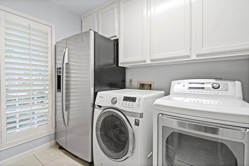 The spacious laundry room easily accommodates a full-sized refrigerator and features built-in storage cabinets, along with a walk-in closet complete with shelving—perfect for storing cleaning supplies, brooms, vacuums, and more.