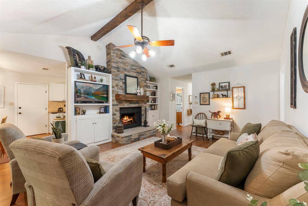 The stone floor-to-ceiling fireplace is a focal point in the living room.  The remote-controlled gaslog fireplace is serviced by a propane tank located in the backyard.  Shelving and storage flank either side of the fireplace, providing storage and display space.
