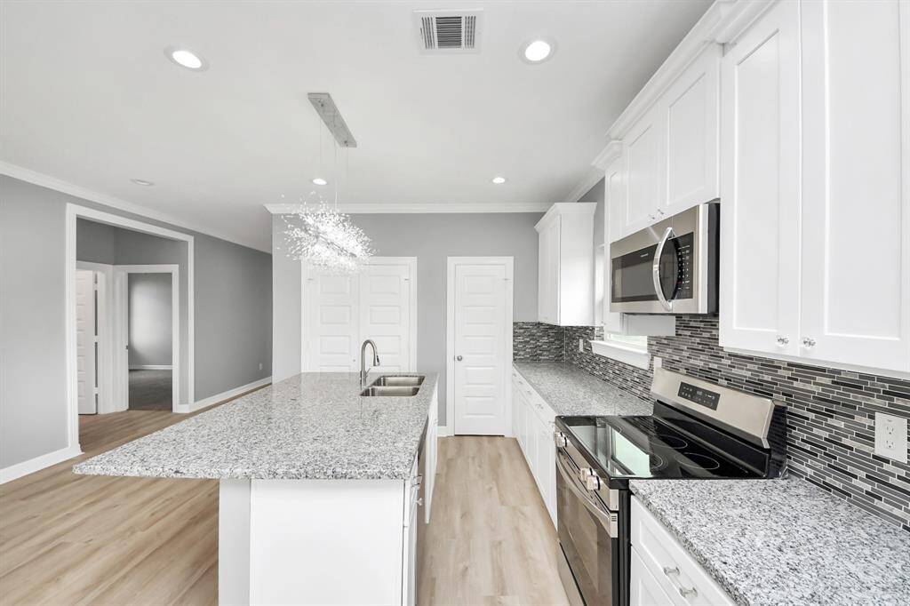 This beautifully designed kitchen offers an abundance of counter and cabinet space, providing plenty of storage to keep everything organized and within reach. The stylish flooring complements the cabinetry perfectly, creating a seamless and inviting look, while the spacious walk-in pantry ensures you’ll never run out of room for all your kitchen essentials.