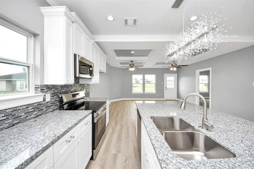 Bright, open, and thoughtfully designed, this kitchen is a perfect blend of comfort and style. The large granite island invites guests to gather, while the stainless-steel range, built-in appliances, and elegant finishes like a mosaic tile backsplash and white painted cabinetry make it a dream space for cooking and entertaining.