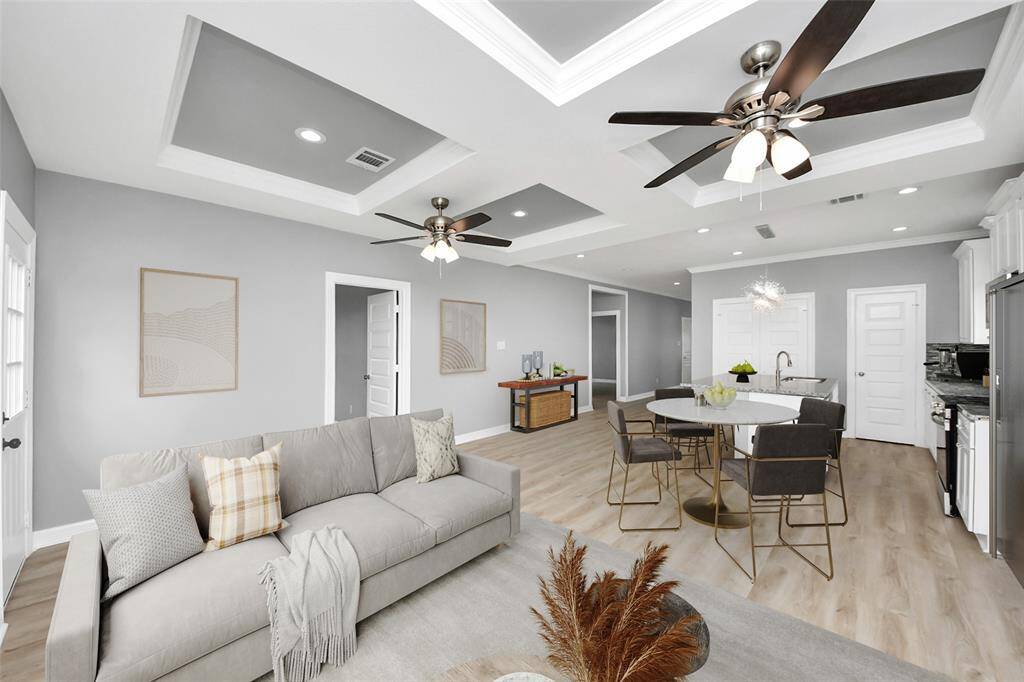 The open-concept living area flows effortlessly into the kitchen, creating a seamless space perfect for everyday living and entertaining. Stunning luxury vinyl plank flooring adds warmth and durability, while elegant crown molding and a beautifully designed tray ceiling enhance the architectural charm, making this space as stylish as it is functional - virtually staged.