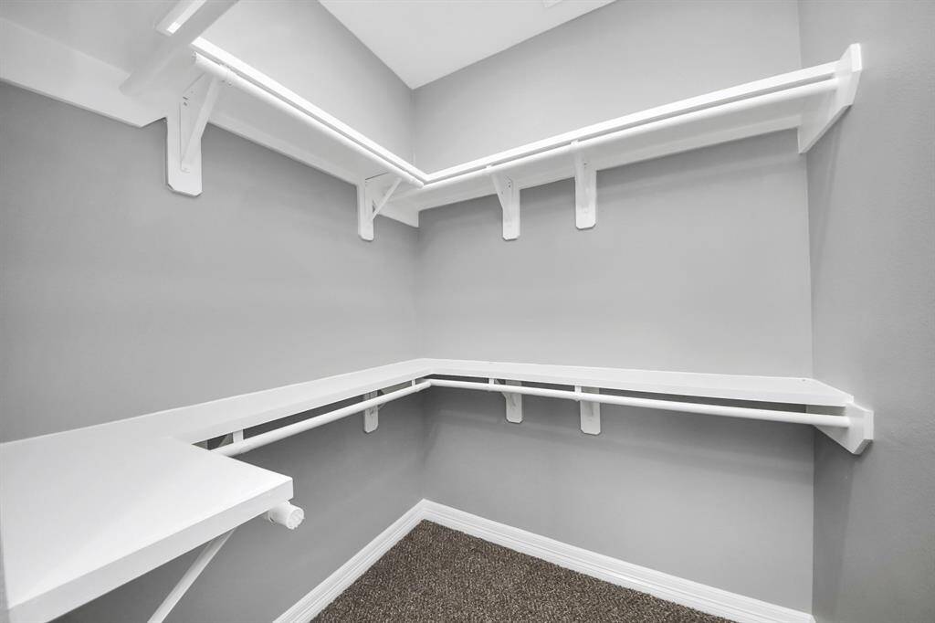 The spacious primary closet is designed for organization and ease, featuring plenty of hanging space, shelves, and thoughtful storage solutions.