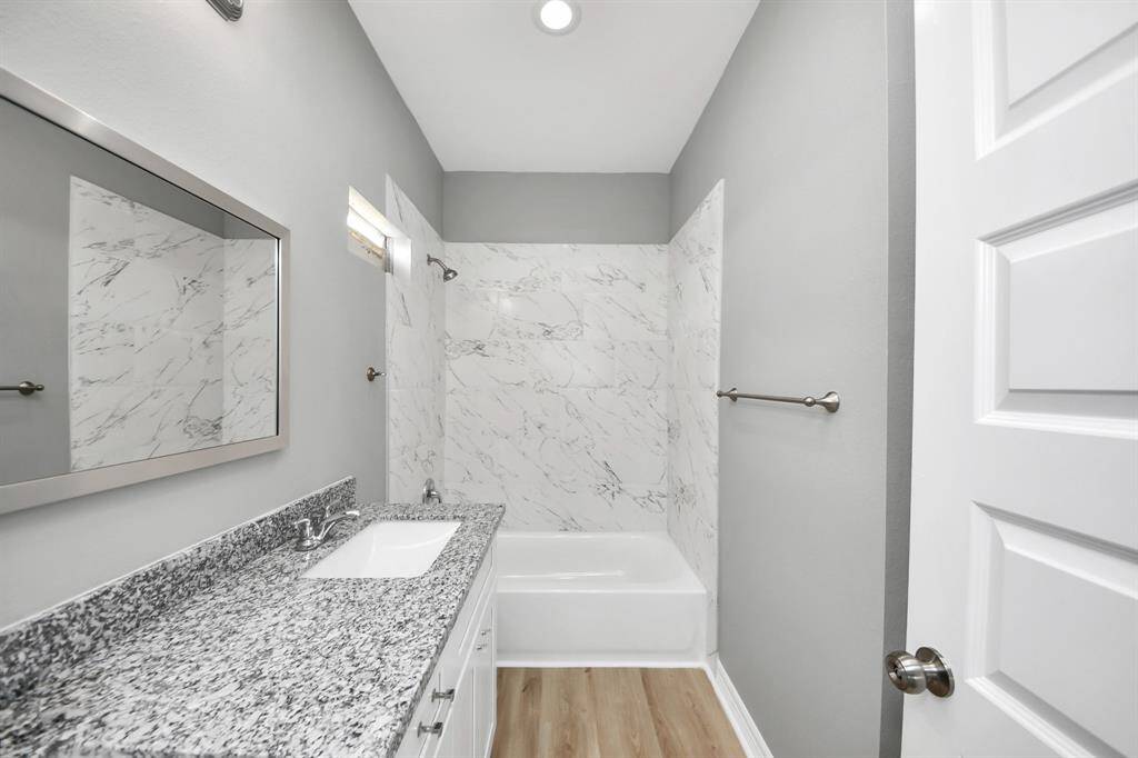 The primary bathroom combines elegance and practicality with exquisite tile work and a soothing neutral color palette. LVP flooring adds a touch of warmth, while recessed lighting enhances the room’s ambiance.