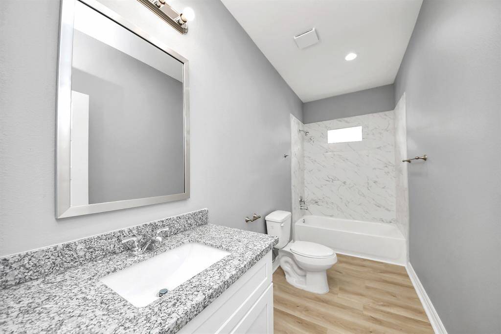 The well-appointed secondary hall bathroom showcases elegant granite countertops, ample cabinet storage, and a convenient tub/shower combo, offering a perfect balance of style and practicality for both family and guests.