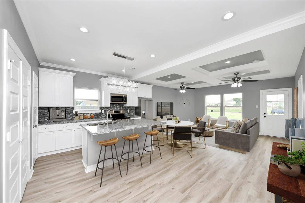 This open-concept floor plan is designed to impress, showcasing upscale finishes such as sleek luxury laminate flooring, elegant crown molding, and sophisticated tray ceilings that add a touch of architectural charm - virtually staged.