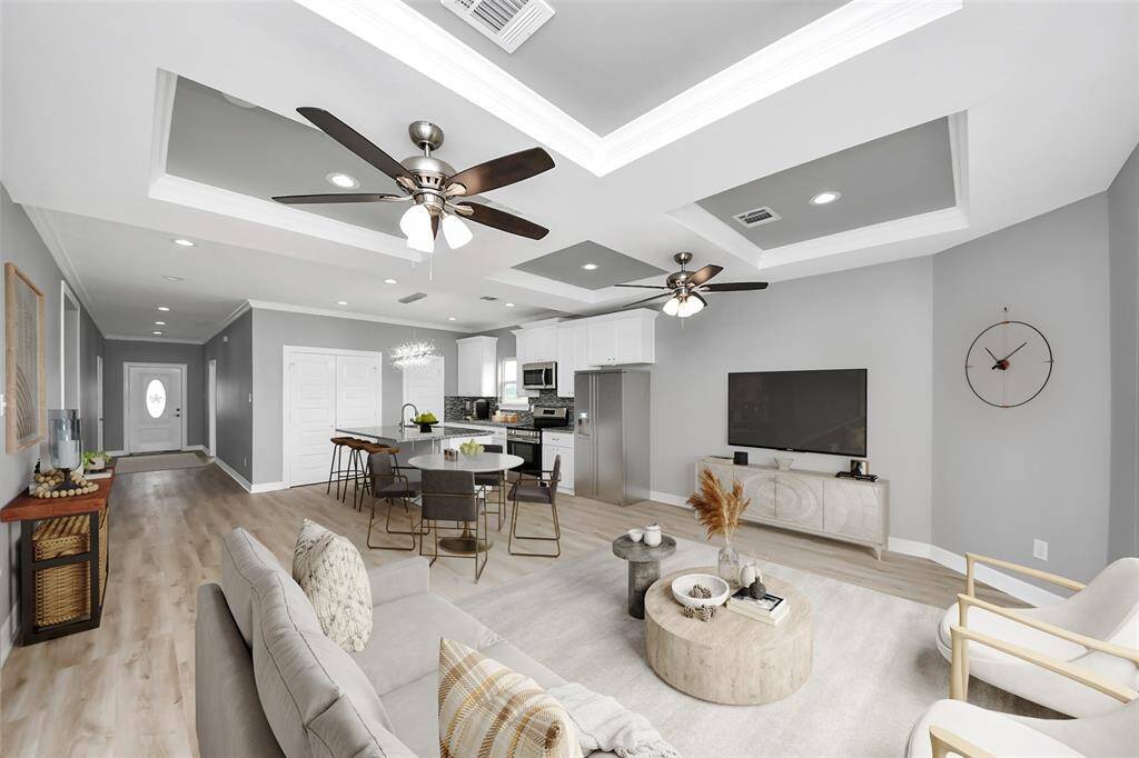 The open-concept living area flows effortlessly into the kitchen, creating a seamless space perfect for everyday living and entertaining. Stunning luxury vinyl plank flooring adds warmth and durability, while elegant crown molding and a beautifully designed tray ceiling enhance the architectural charm, making this space as stylish as it is functional - virtually staged - virtually staged.