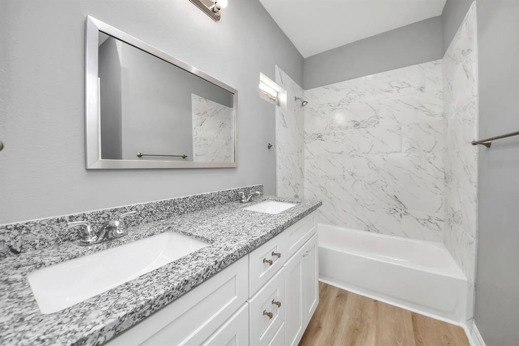 The primary bathroom offers a perfect blend of elegance and functionality, featuring beautiful tile work that adds a touch of sophistication, a spacious granite vanity with dual sinks for added convenience, and ample cabinet space for all your storage needs.