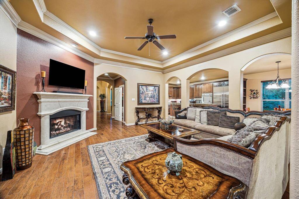 The open-concept layout seamlessly connects the living room to the kitchen, breakfast area, and sunroom. Crown molding, recessed lighting, and archways frame the space while offering views of the backyard retreat beyond.