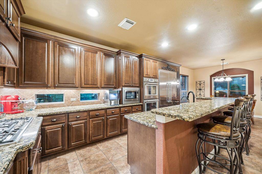 This beautifully designed kitchen combines style and function with a Thermador 5-burner gas range and a convenient under-range drawer system for easy access to pots and pans. A Fischer-Paykel double refrigerator with RO-filtered water dispenser, Bausch dishwasher, and a second RO-ready tap add convenience and efficiency. Tile flooring, recessed lighting, and arched entryways complete this thoughtfully appointed culinary space.
