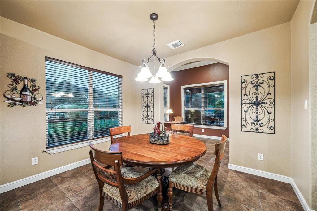 This light-filled breakfast room offers serene views of the side yard through large windows and is ideally located between the kitchen and sunroom, creating a seamless flow for everyday living and entertaining. Neutral tile flooring and a classic light fixture complete the space.