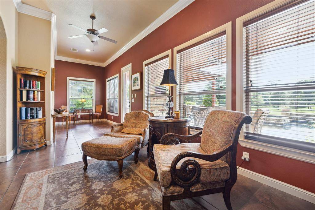 Filled with light, the sunroom offers a seamless extension of the home's living spaces, with rich tile flooring that flows directly from the kitchen for a cohesive look. Expansive windows frame peaceful backyard and lake views, while the warm wall tones and elegant crown molding create a cozy yet refined setting. Whether used for morning coffee, afternoon reading, or casual entertaining, this charming space invites relaxation and connection to the outdoors.