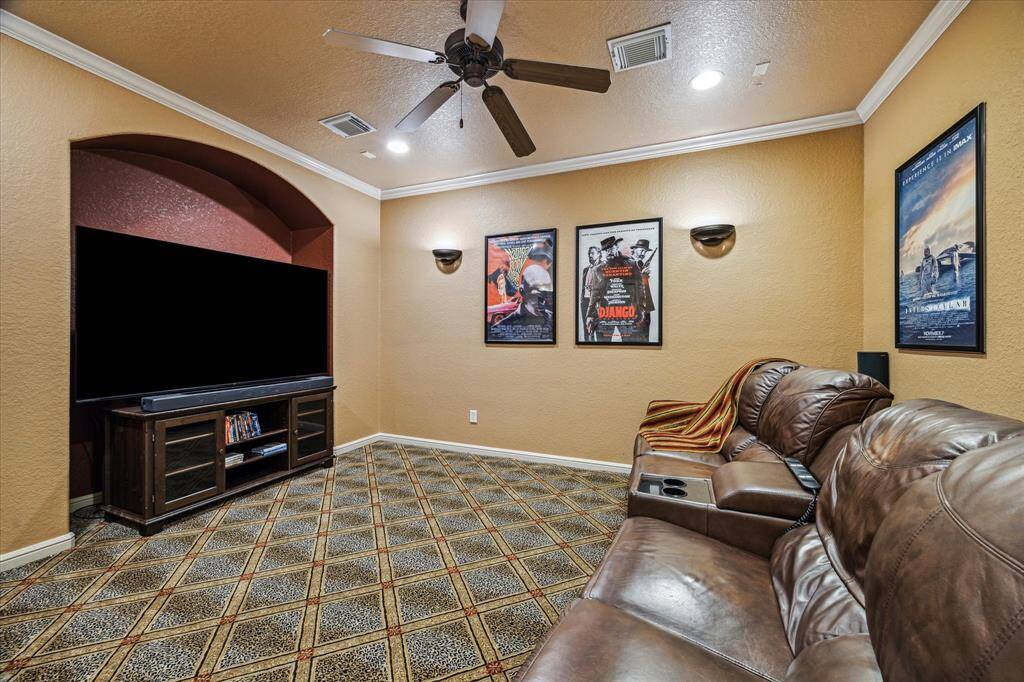 Designed for the ultimate movie night experience, this dedicated media room features plush carpeting for added comfort and sound absorption. Crown molding, recessed lighting, and wall sconces create an ideal cinematic atmosphere, while the spacious layout easily accommodates theater seating and a large screen setup.