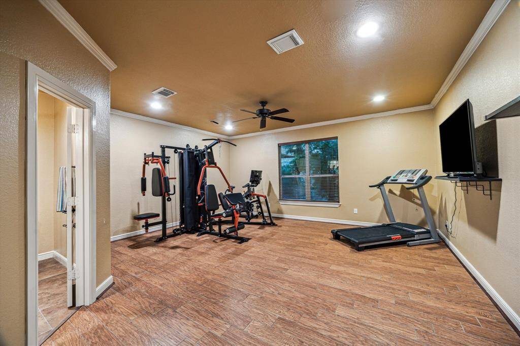 Currently used as a home gym, this flexible first-floor room offers endless possibilities—easily converted into a fifth bedroom, guest suite, or private office. It features direct access to the garage, a walk-in closet, and a full ensuite bath for added convenience. With durable wood-like tile flooring, recessed lighting, and generous dimensions, this space adapts beautifully to fit your lifestyle needs.