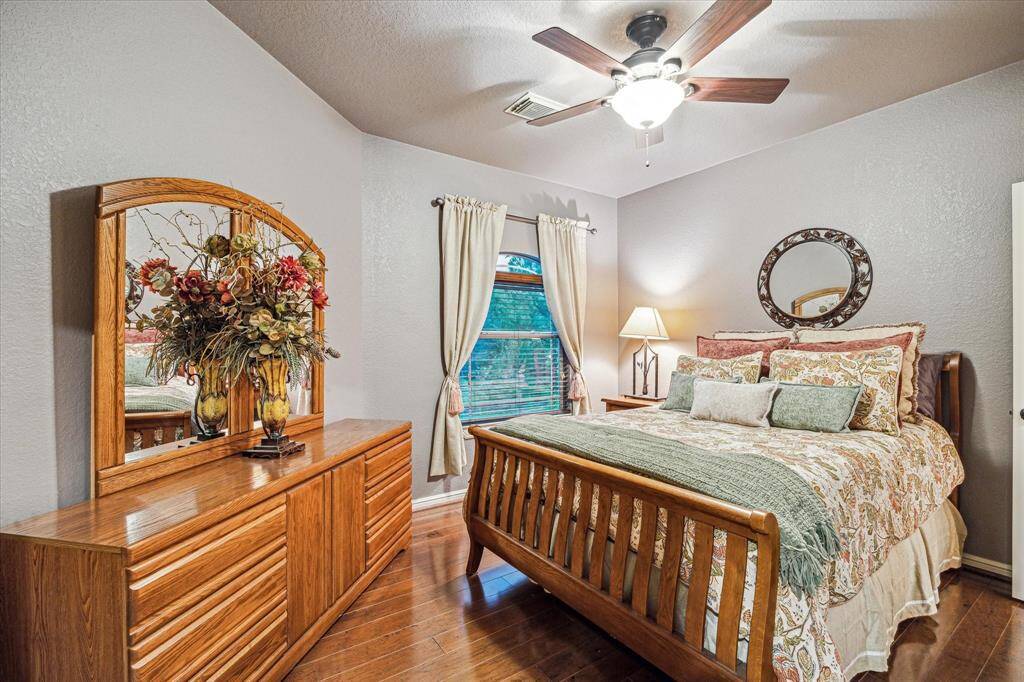 his cozy guest room offers comfort and charm with rich wood flooring, soft neutral wall tones, and a ceiling fan for added comfort. A large window allows natural light to fill the space, while the room’s layout easily accommodates a full bedroom suite. A perfect retreat for overnight guests or extended stays.
