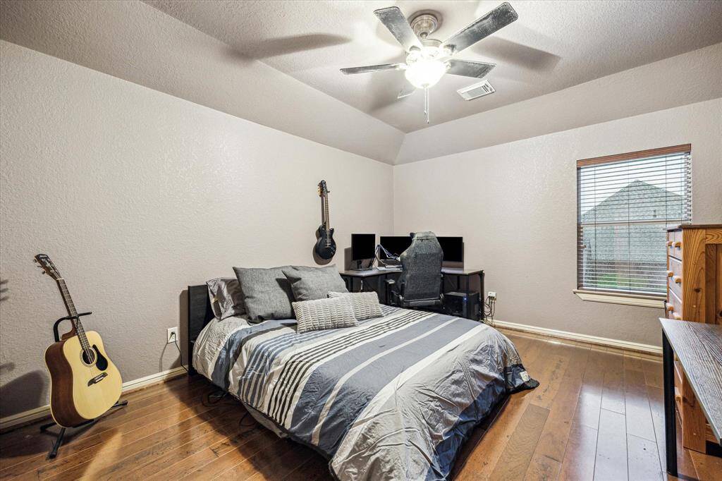 Privately situated upstairs, this secondary bedroom offers a quiet and comfortable retreat, separate from the other guest rooms. Warm wood flooring, soft neutral tones, and a ceiling fan create a cozy atmosphere, while a window overlooking the side yard adds a peaceful touch. Ideal for a guest suite, teen room, or home office.