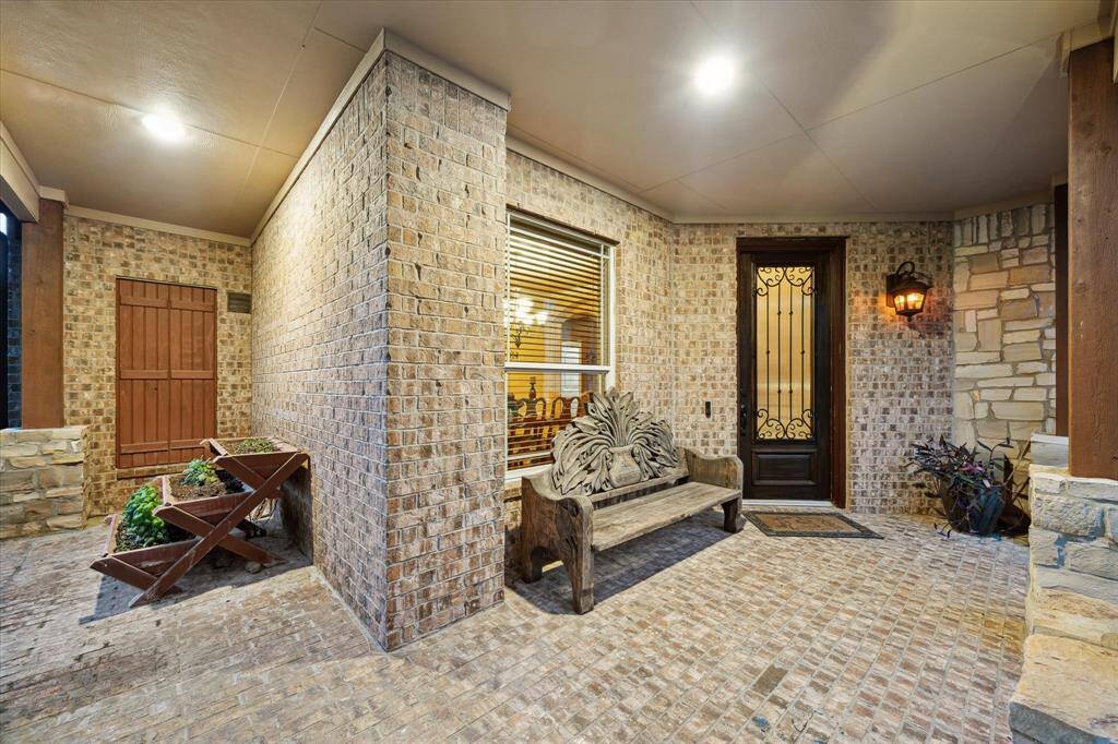 This charming bricked front porch features a classic blend of brick and stone accents, offering a warm and welcoming entry. The covered design provides shade and shelter, while recessed lighting enhances evening ambiance.