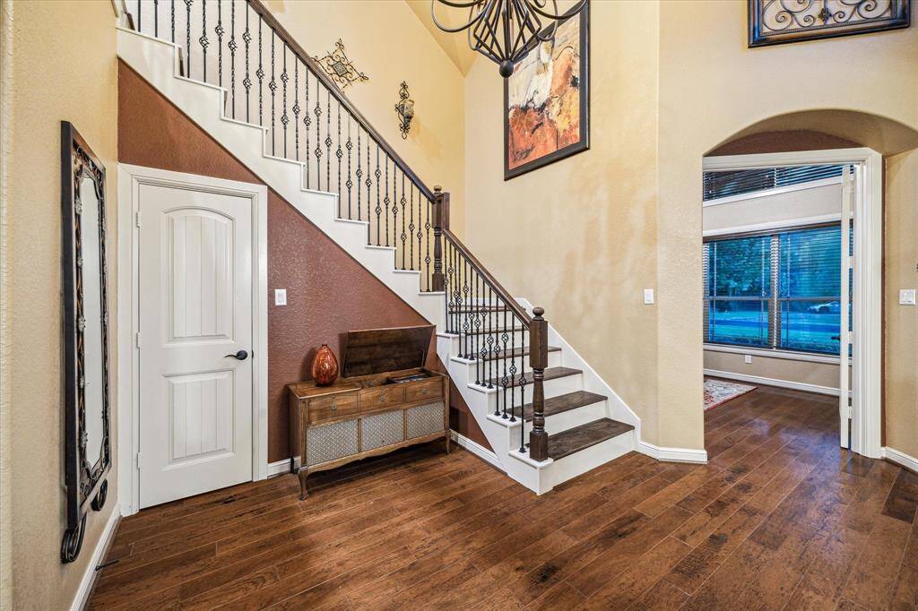 Rich wood floors, iron balusters, and soaring ceilings create a grand welcome, while arched openings lead to both the formal dining room and a private study.