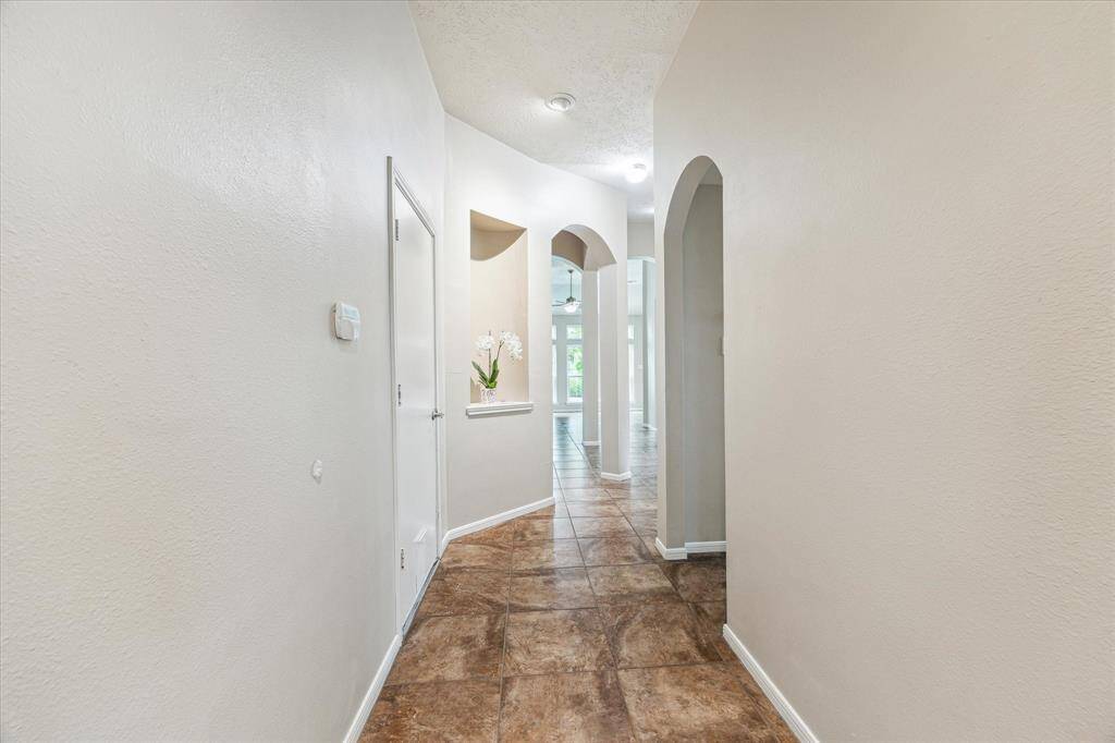 Inviting entryway with elegant archways, recessed niche detail, and warm tile flooring leading to the bright and open main living area.