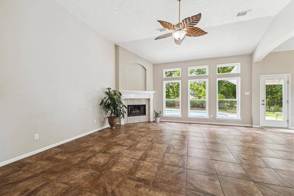 The living space highlighted by a fun leaf-inspired ceiling fan plus access to the outdoor oasis through the back door on the right. This home features double pane windows throughout.