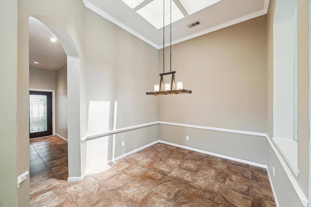 Introducing the formal dining room, complete with an elegant chandelier and a skylight that brightens the space with natural light.