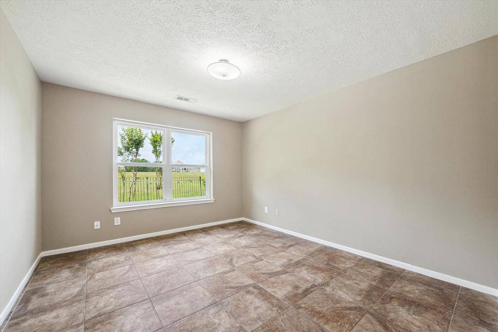 This flexible room offers a lovely view of the picturesque side yard, featuring tile flooring and a modern light fixture.