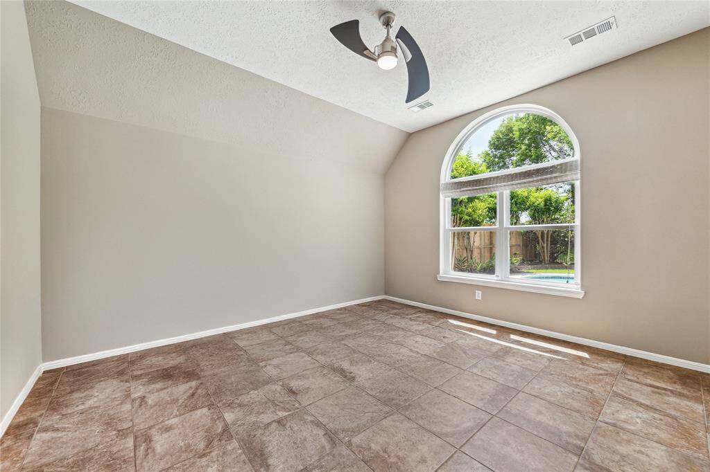 The primary bedroom offers a peaceful retreat with a view of the backyard and a sleek, modern ceiling fan for added comfort.