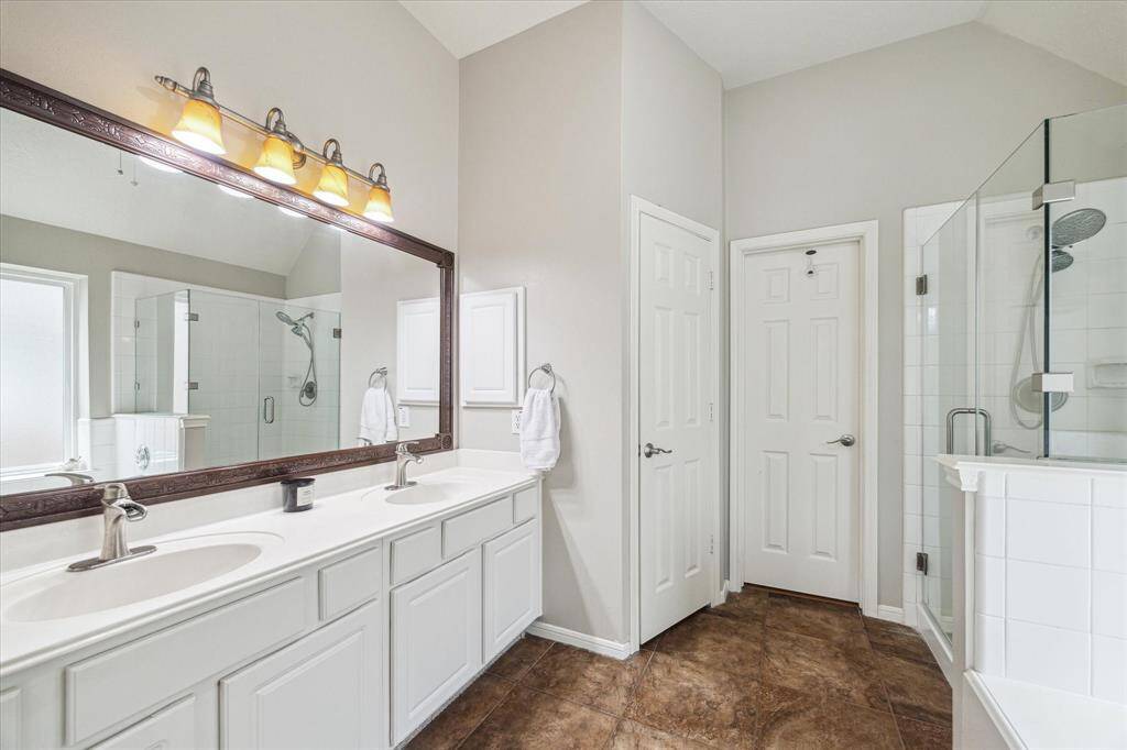 The primary bathroom features dual sinks, a separate walk-in shower, a bathtub, and an attached mirror with overhead lighting.