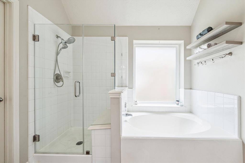 The spa-inspired bathroom offers a walk-in shower with sleek frameless glass, a built-in seat for added comfort, and a luxurious soaking tub—perfect for unwinding in style.