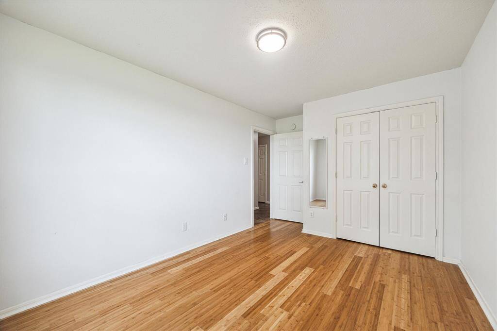 Another view of the secondary bedroom which includes a hanging wall mirror and closet.