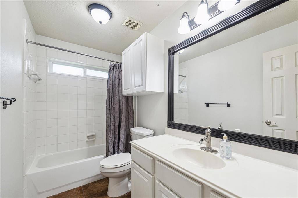 The full bathroom features a tub and shower combo, with an attached mirror and overhead lighting, conveniently located for easy access from both secondary bedrooms.