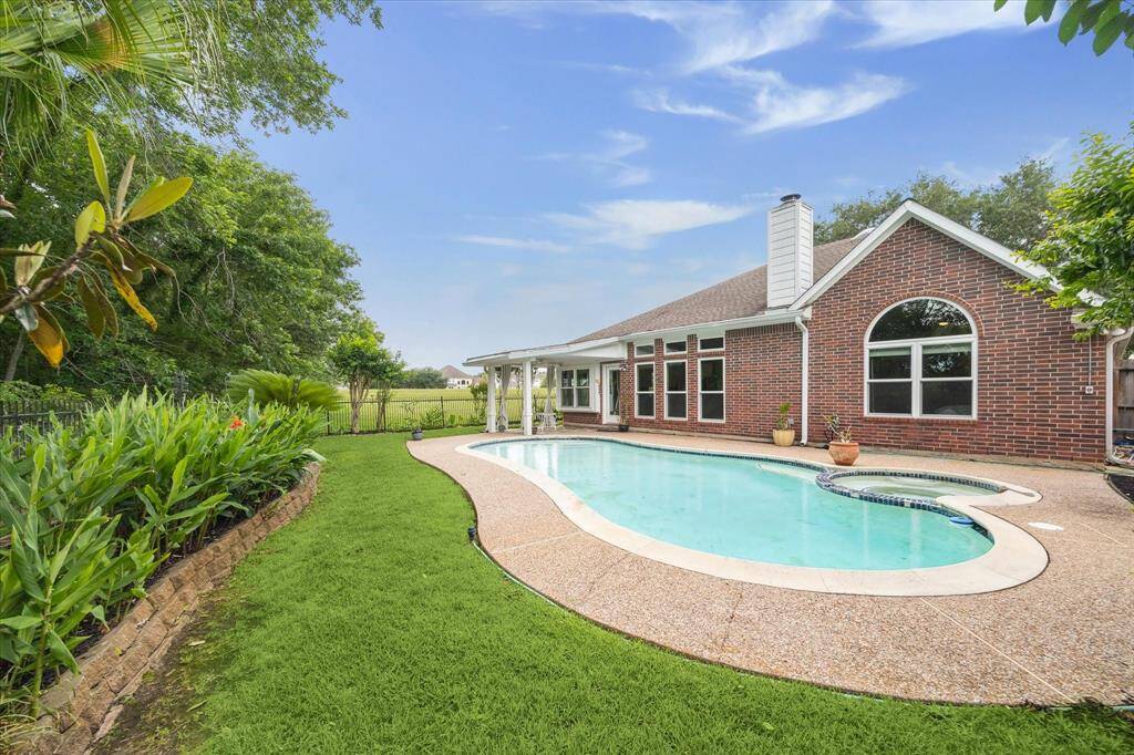 Stunning view of the backyard swimming pool, surrounded by lush greenery and no rear or side neighbors, with elegant wrought iron fencing—creating a serene atmosphere that makes you feel like you're on vacation every day.