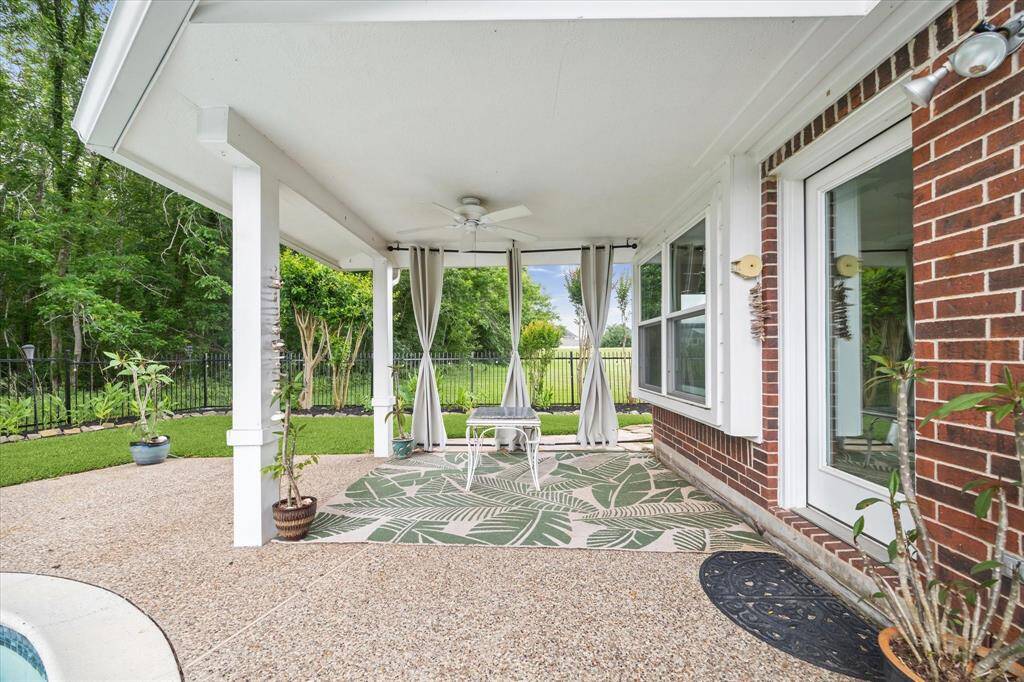 Covered back patio with curtains that create a peaceful atmosphere, complemented by a ceiling fan for extra relaxation.