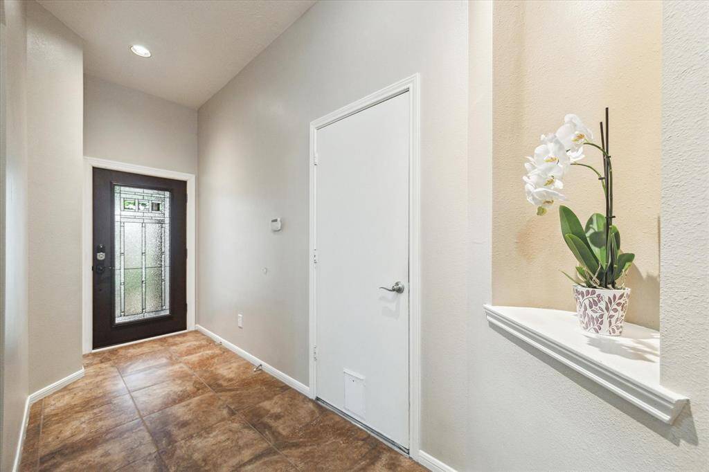 Welcoming front foyer with a stylish glass-paneled door, neutral tones, and access to the two car attached garage.