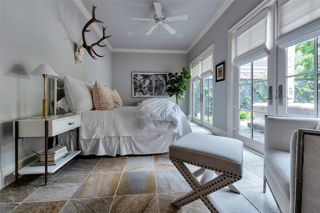 The downstairs bedroom blends comfort and elegance with an abundance of natural light Large French doors and windows with custom roman shades open up to the backyard patio, bringing the outdoors in. This room would also be a great exercise room or cabana room!