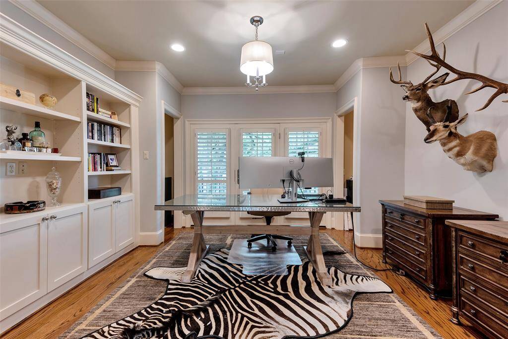 This sophisticated home office features built-in shelving, rich wood floors, and access to outdoor balcony. A spacious layout and refined finishes create a productive yet stylish workspace.