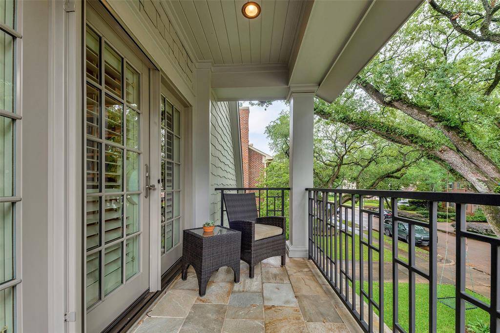 This charming balcony off the home office offers a peaceful retreat among the treetops, with views of the majestic oak equipped with lightning protection and evening downlighting. Slate tile flooring and cozy seating make it the perfect perch for a morning coffee or sunset unwind.