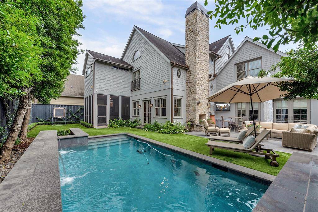 This backyard oasis features a sleek pool with tranquil water features, a cozy stone fireplace, and a shaded lounge area perfect for relaxing or entertaining. Artificial turf and lush landscaping create a low-maintenance, private retreat for all seasons.