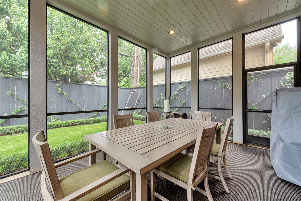 This inviting screened-in porch offers a serene space for outdoor dining and entertaining, free from bugs and weather. Surrounded by lush landscaping and seamless access to the backyard and outdoor kitchen.