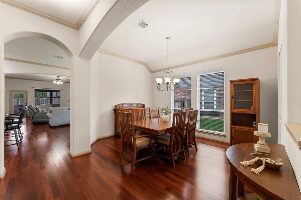 The elegant formal dining room is defined by graceful archways and enhanced by tall windows that fill the space with natural light. Hardwood flooring continues here, complemented by high ceilings and classic trim work—an inviting setting for gatherings both intimate and grand.