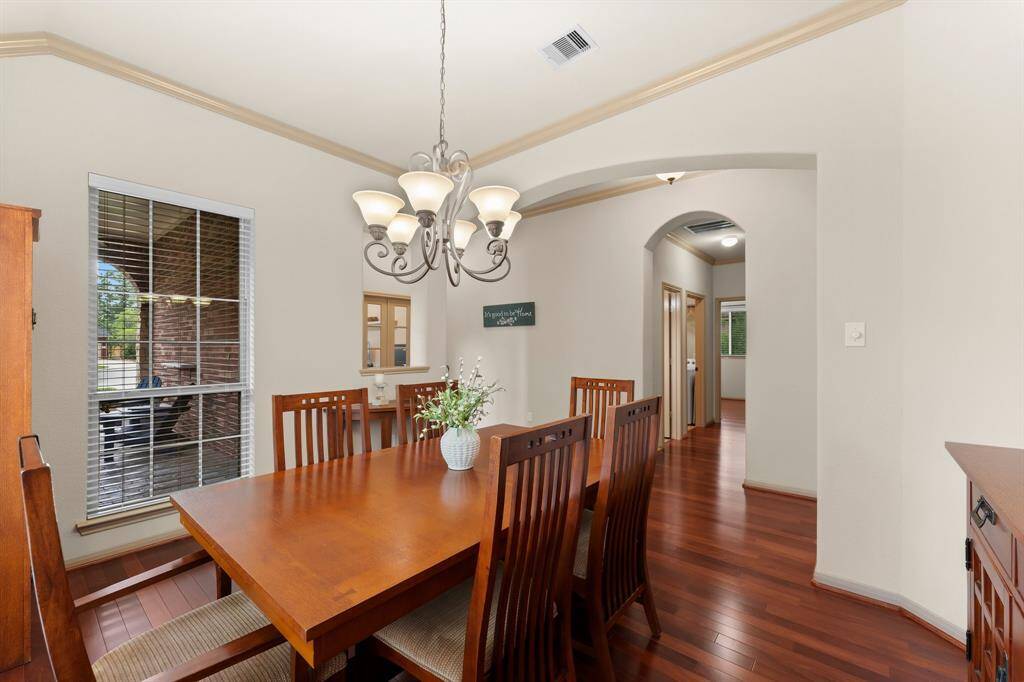 The elegant formal dining room is defined by graceful archways and enhanced by tall windows that fill the space with natural light. Hardwood flooring continues here, complemented by high ceilings and classic trim work—an inviting setting for gatherings both intimate and grand.
