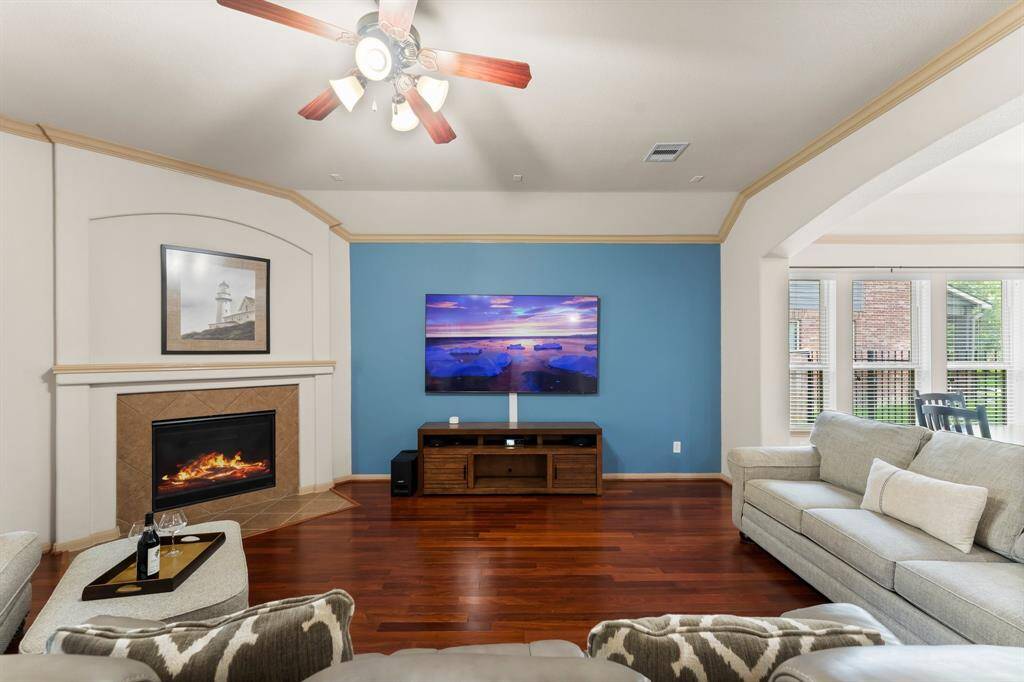 Cozy up by the elegant gas fireplace in this inviting living room, accented by a custom blue feature wall and rich hardwood flooring.